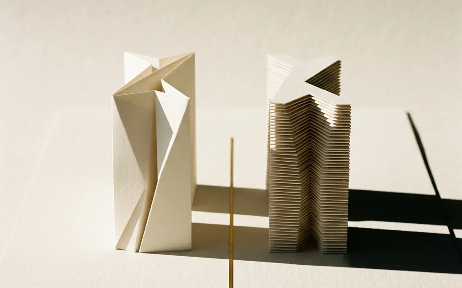 Deux maquettes en papier de même taille côte à côte, l’une d’un seul pli net, l’autre faite de nombreuses couches visibles.